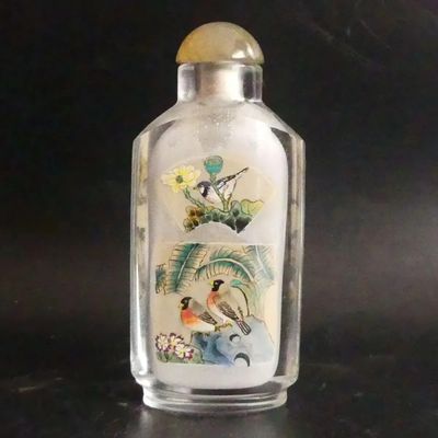 a glass bottle with a painting on it on a table