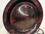 une assiette rouge et noire posée sur un support, sur une table