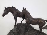 statue of two horses standing on a rock on a white background