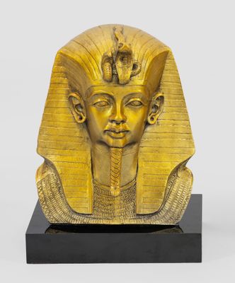 une statue en or représentant un pharaon égyptien, posée sur un socle noir