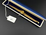 une montre en or dans un coffret bleu muni d'une étiquette