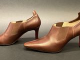 a pair of brown leather ankle boots with red soles