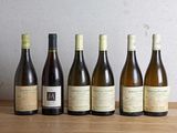 six bouteilles de vin sont alignées sur une table en bois