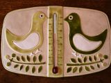 a picture of a thermometer with two birds on it