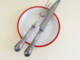 two forks and a knife in a red and white plate