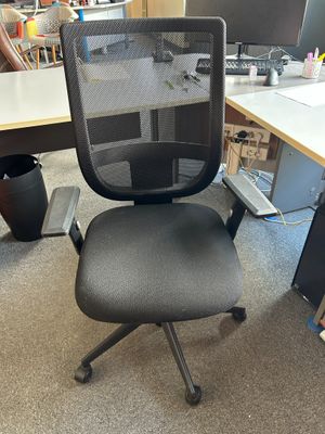 a black office chair sitting in front of a computer desk
