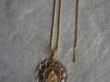 a close up of a gold necklace with a picture of a woman on it