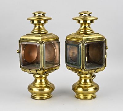 une paire de lampes en laiton et en verre posées sur des socles, sur fond blanc
