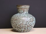 un vase bleu posé sur une table, sur fond noir
