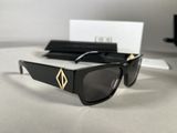 the sunglasses are black and have a gold emblem on them