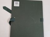 an open book with a green cover on a white table