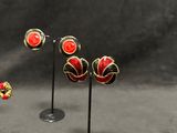 several pairs of red and black earrings and ear rings on a black background