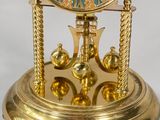 a gold clock that is sitting on a stand