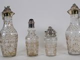 four pieces of glass and silverware on a white surface