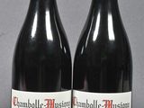 two bottles of red wine sitting next to each other on a table