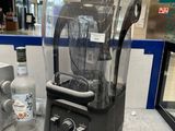 un mixeur posé sur un plan de travail, à côté d'une bouteille de vodka
