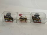 three toy cars in a clear box on a white surface