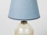 une lampe en verre surmontée d'un abat-jour bleu