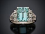 un gros plan d'une bague sertie d'une émeraude entourée de diamants