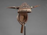 a wooden mask with horns and a hat on a stand