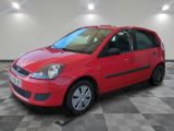 une Ford Fiesta rouge garée dans une grande pièce au sol à carreaux