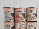 six tins of canned food are stacked on a white surface