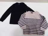 two sweaters are sitting on a white surface one is black and the other is pink