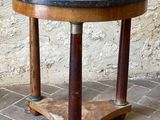 une petite table avec un plateau en marbre posée sur un sol en briques