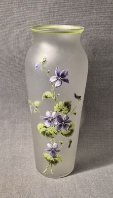 un vase en verre sur lequel sont peintes des fleurs violettes