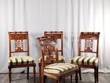 trois chaises en bois avec des assises rembourrées à rayures, devant un rideau blanc