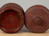 pair of red pottery vases on wooden table with grey background