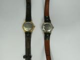 two watches are sitting next to each other on a white surface