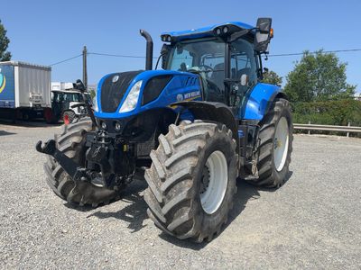 a blue tractor parked in a parking lot next to a truck