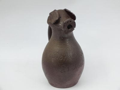 a brown vase with a dog on it on a white surface