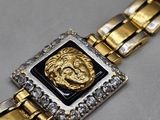 a close up of a gold and black bracelet with a lion head on it