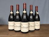 six bottles of wine are lined up on a wooden table