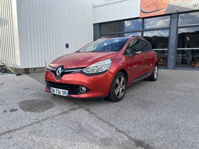 une voiture rouge garée devant un immeuble, sur un parking
