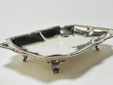 an antique silver plate on a stand on a white surface