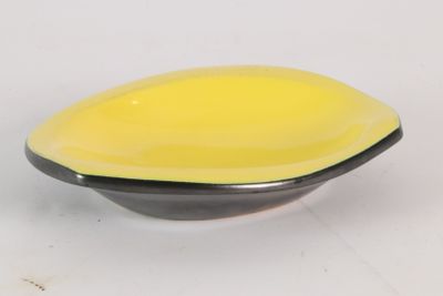 un bol jaune et noir posé sur une surface blanche