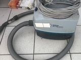 un aspirateur posé au sol, muni d'un tuyau