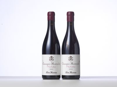 two bottles of red wine sitting on top of a white table