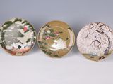 three plates with birds and flowers painted on them sitting on a table