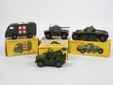 Quatre véhicules militaires miniatures sont posés dans une boîte sur une surface blanche