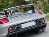 the rear end of a silver porsche sports car driving down a road