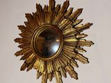 a gold sunburst hanging on the wall above a mirror
