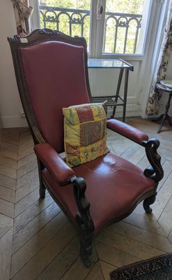 a red chair with a pillow on it in front of a window