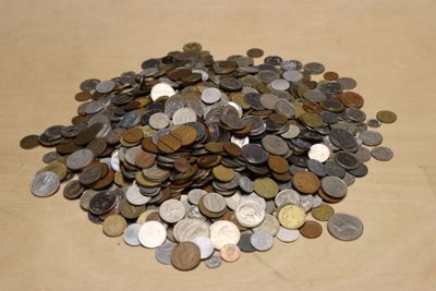 a pile of coins sitting on a table next to a cell phone
