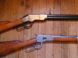 trois types d'armes à feu différents, posés côte à côte sur un plancher en bois