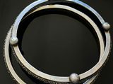 deux bracelets en argent posés sur une surface noire avec un fond noir