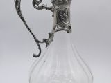 an antique silver plated glass pitcher with a floral design on the handle